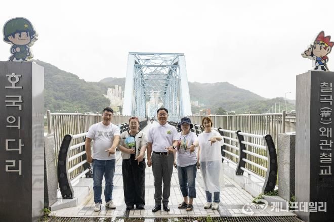 왜관읍문화도시사업추진단 임원진과 김재욱 칠곡군수가 호국의다리 앞에서 기념 촬영을 하고 있다. 이들은 120년의 세월을 품은 다리 위에, 지역 주민들의 기억을 모아 사진전 ‘120년의 추억 나들이’를 함께 준비했다.